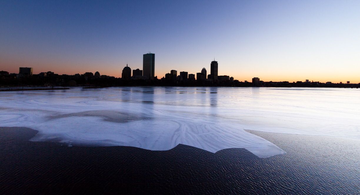 An jagged ice sheet mimics the Boston skyline, reflected in the Charles River as the sun sets over the city.  The tall building on the left is the John Hancock Tower; the building to the right with antennas is the Prudential Tower.  This shot was taken from the Longfellow Bridge, looking south west, after an interminably long wait in the freezing cold for the sun to set low enough for the colours to leak into the ice.
